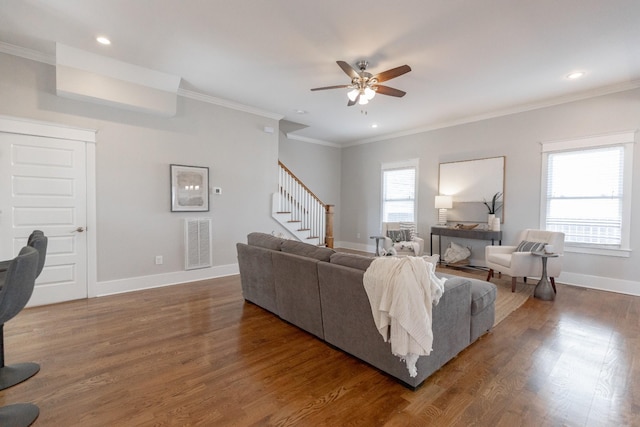 living area with wood finished floors, visible vents, baseboards, stairway, and crown molding