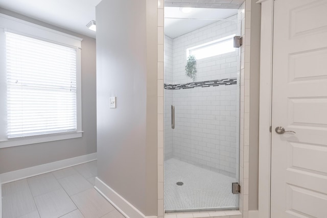 bathroom with a wealth of natural light, visible vents, a shower stall, and baseboards