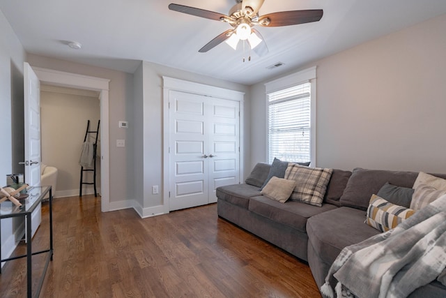 living room featuring a ceiling fan, baseboards, visible vents, and wood finished floors