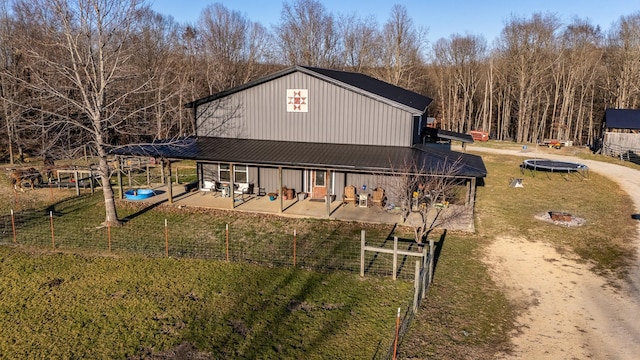 exterior space featuring a trampoline, metal roof, a lawn, and a patio