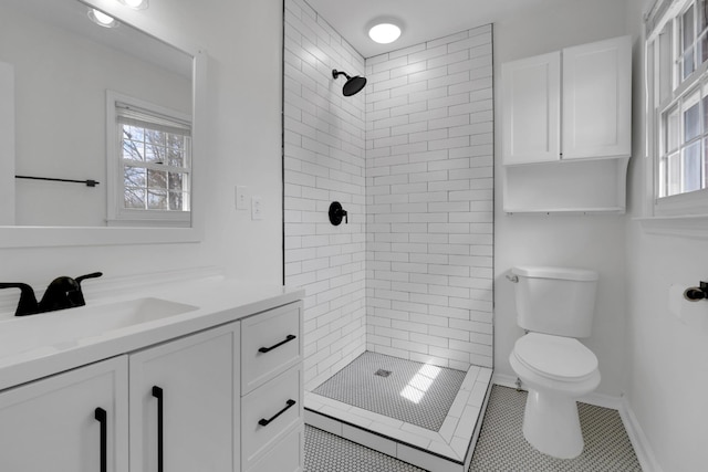 full bath featuring baseboards, toilet, tile patterned flooring, a tile shower, and vanity