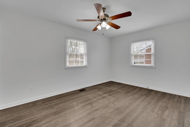 spare room featuring a wealth of natural light, wood finished floors, visible vents, and baseboards