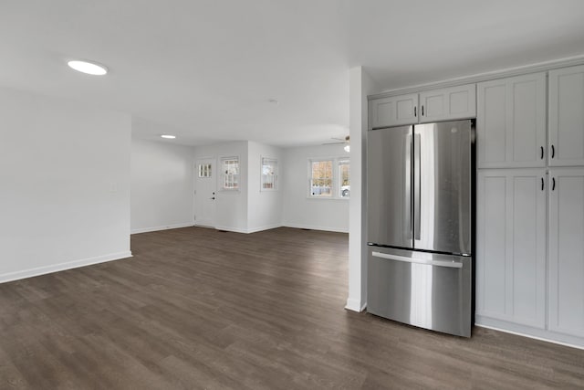 kitchen featuring open floor plan, dark wood-style flooring, freestanding refrigerator, and baseboards