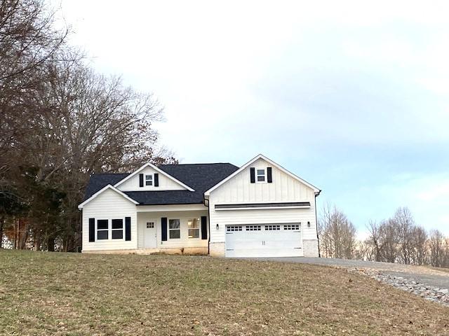 view of front of home with driveway, a front lawn, board and batten siding, and an attached garage