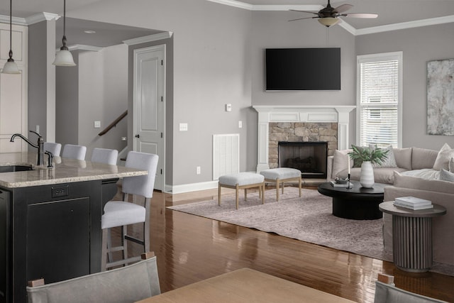 living area with dark wood-style floors, ceiling fan, visible vents, and ornamental molding