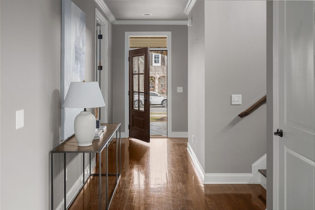 foyer featuring baseboards, stairway, wood finished floors, and crown molding