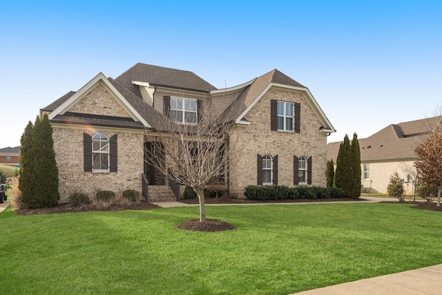 view of front of property featuring brick siding, a front lawn, and a shingled roof