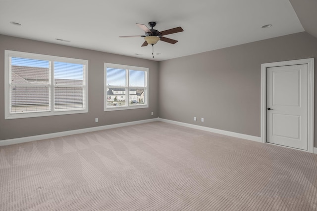 unfurnished room with a ceiling fan, light colored carpet, visible vents, and baseboards