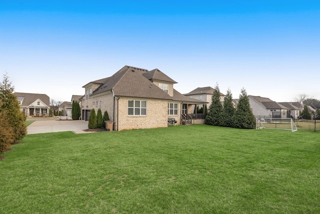 back of house with a garage, brick siding, fence, driveway, and a yard