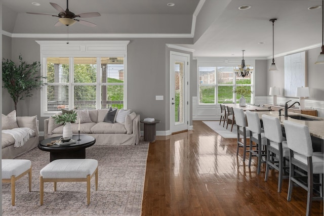 living room featuring ornamental molding, dark wood-style flooring, and ceiling fan with notable chandelier