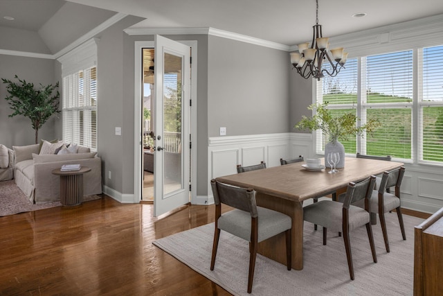 dining room with a wainscoted wall, crown molding, light wood-type flooring, a chandelier, and a decorative wall