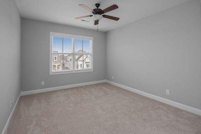 spare room with ceiling fan, visible vents, baseboards, and light colored carpet