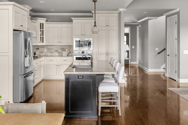 kitchen featuring backsplash, appliances with stainless steel finishes, ornamental molding, a sink, and light stone countertops