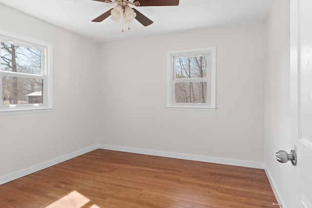 empty room with ceiling fan, light wood finished floors, and baseboards