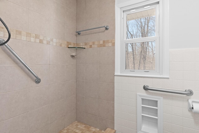 bathroom with a tile shower and tile walls