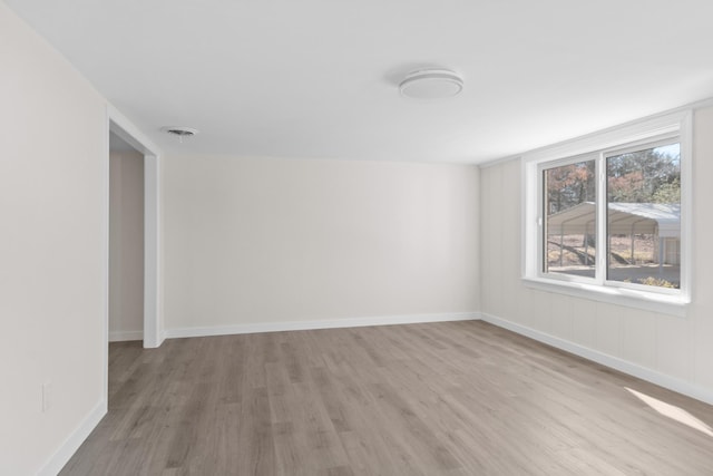 spare room with light wood-style floors, visible vents, and baseboards