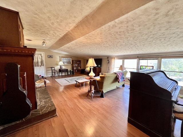 living room with lofted ceiling, plenty of natural light, a textured ceiling, and wood finished floors