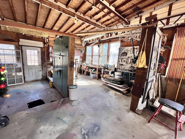 miscellaneous room featuring a healthy amount of sunlight, a workshop area, and unfinished concrete floors