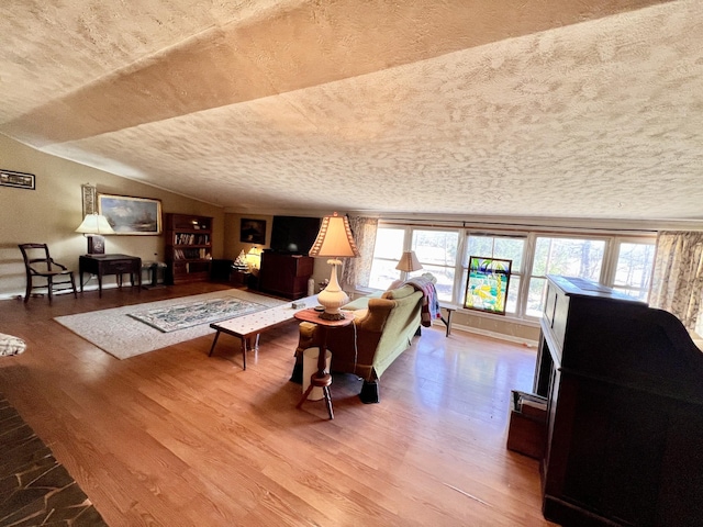 living room with a textured ceiling, vaulted ceiling, and wood finished floors