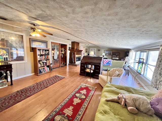 living room featuring a textured ceiling, wood finished floors, visible vents, a ceiling fan, and vaulted ceiling