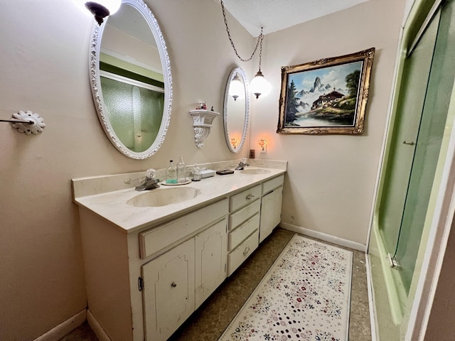 full bath featuring a shower with shower door, a sink, baseboards, and double vanity