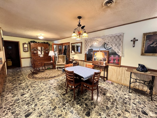 dining space featuring visible vents, a wainscoted wall, ornamental molding, a textured ceiling, and wood walls