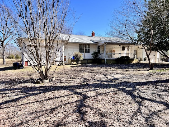 view of front of property featuring a porch, metal roof, and a chimney