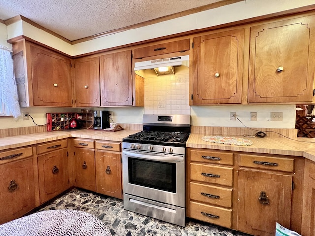 kitchen featuring under cabinet range hood, brown cabinets, light countertops, and gas stove