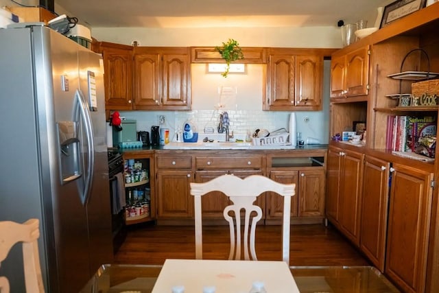 kitchen with a sink, tasteful backsplash, stainless steel fridge, and brown cabinets