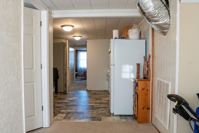 hallway featuring carpet flooring, visible vents, and crown molding