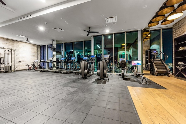 workout area featuring brick wall, floor to ceiling windows, and a ceiling fan