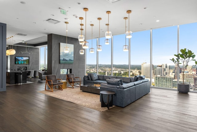 living area with a wall of windows, a wealth of natural light, visible vents, and wood finished floors