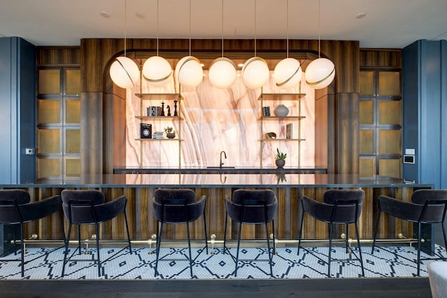 bar with pendant lighting, indoor wet bar, and a sink