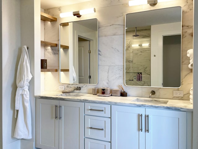 full bath featuring a walk in shower, double vanity, tasteful backsplash, and a sink