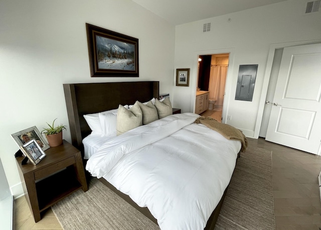 bedroom with ensuite bathroom, baseboards, visible vents, and electric panel