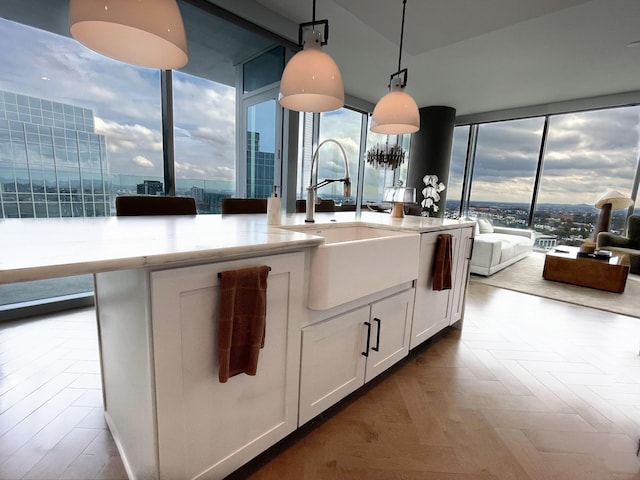 kitchen featuring a healthy amount of sunlight, a sink, decorative light fixtures, and white cabinets