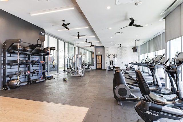 workout area featuring ceiling fan, plenty of natural light, visible vents, and a wall of windows