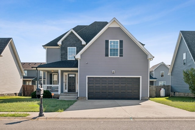 traditional-style house with a porch, concrete driveway, an attached garage, a front yard, and fence