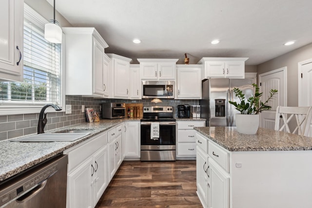 kitchen with stainless steel appliances, backsplash, a sink, and white cabinetry