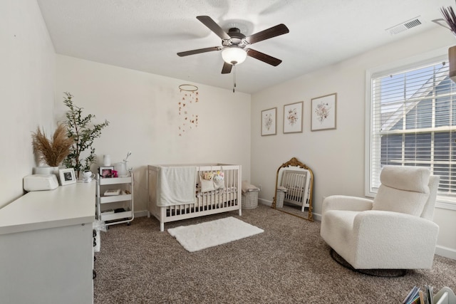 bedroom with carpet, visible vents, a crib, and baseboards