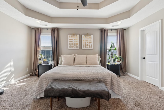 carpeted bedroom with a tray ceiling and baseboards