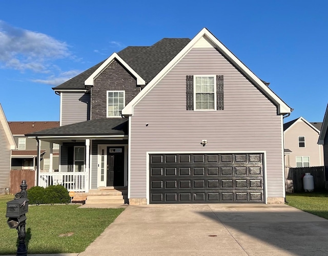 traditional home with covered porch, a front yard, fence, a garage, and driveway