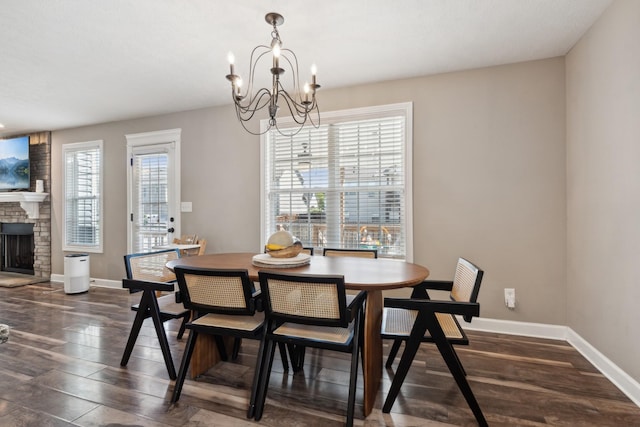 dining space featuring an inviting chandelier, a fireplace, baseboards, and dark wood finished floors