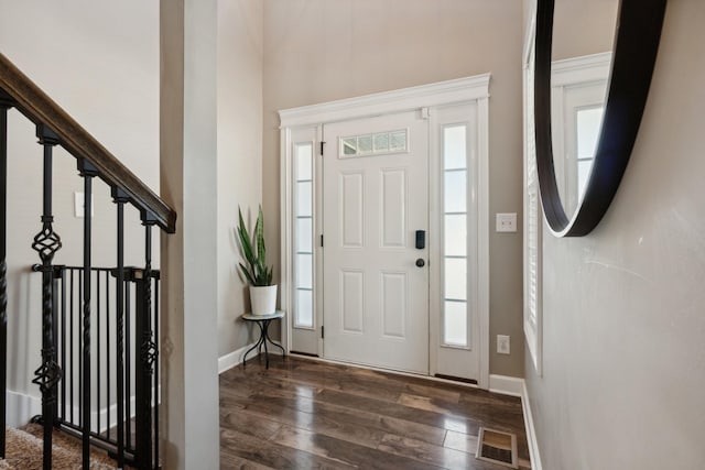 entryway with dark wood-style floors, baseboards, visible vents, and a healthy amount of sunlight