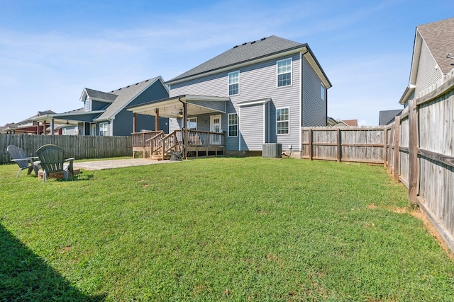 rear view of property with ceiling fan, a fenced backyard, central AC, a lawn, and a wooden deck