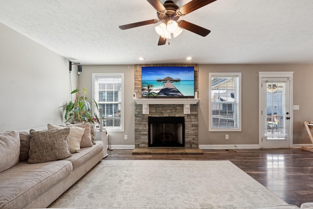 living area with a textured ceiling, a fireplace, baseboards, and wood finished floors