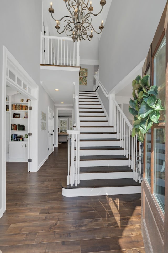 foyer entrance with an inviting chandelier, stairway, a high ceiling, and wood finished floors