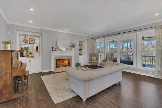 living area featuring baseboards, built in features, dark wood-style floors, a premium fireplace, and crown molding