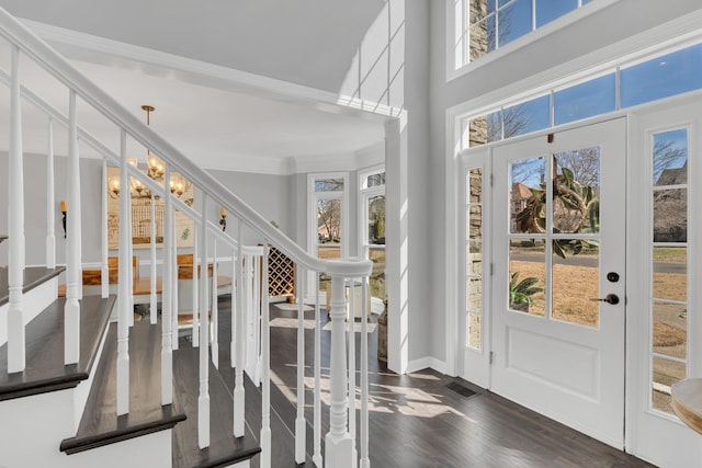 entryway featuring dark wood-style flooring, ornamental molding, stairway, and an inviting chandelier