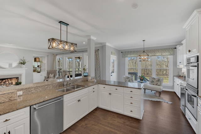 kitchen featuring dark wood-style floors, a warm lit fireplace, a sink, and stainless steel dishwasher